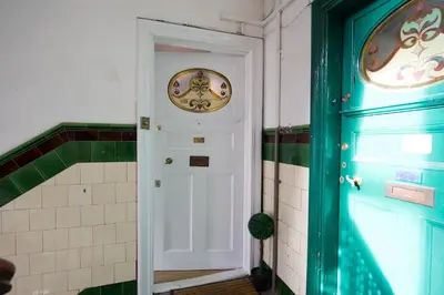 a hallway with a white door and a clock on the wall at PREMIER - Crathie View Apartment in Glasgow
