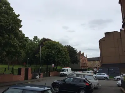 a parking lot with parked cars in a city at PREMIER - Crathie View Apartment in Glasgow