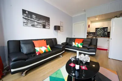 a living room with two black couches and a table at PREMIER - Crathie View Apartment in Glasgow