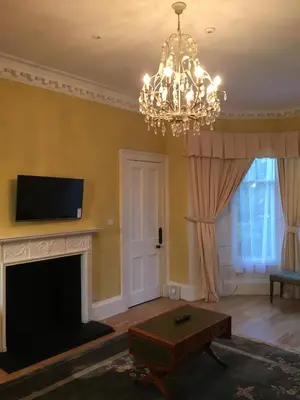 a living room with a fireplace and a chandelier at Lanark Residence in Edinburgh