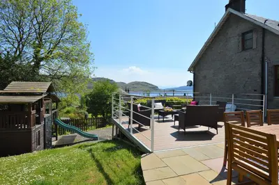 a deck with a playground and a house at Aldersyde in Tighnabruaich