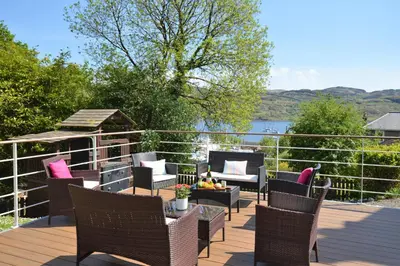 a deck with chairs and a table and a gazebo at Aldersyde in Tighnabruaich