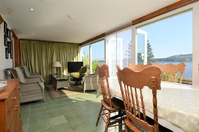 a living room with a table and chairs and a balcony at Ardmun House in Dunoon