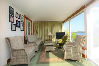 a living room with wicker chairs and a television at Ardmun House in Dunoon