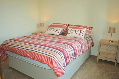 a bedroom with a bed with a striped blanket and two lamps at Clydeside Villa in Dunoon