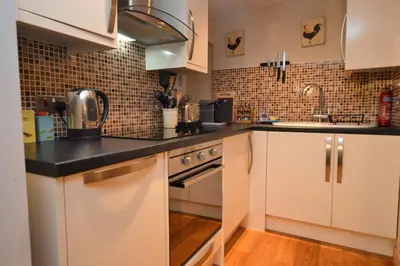 a kitchen with white cabinets and black counter tops at Newton Cottage South in Inveraray