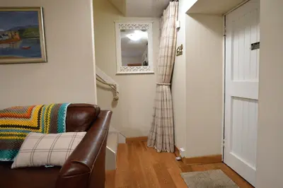a living room with a leather chair and a mirror at Newton Cottage South in Inveraray