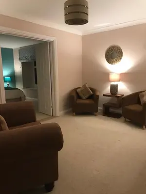 a living room with a couch and chairs and a lamp at Crofthead Farm House in Tarbolton