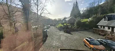 an orange car parked in a driveway next to a house at Ben Lomond Cottage in Arrochar