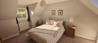 a bedroom with a large bed and a window at Ben Lomond Cottage in Arrochar
