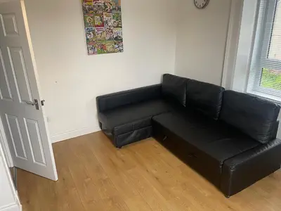 a black leather couch in a living room at Elder Park Apartments in Glasgow