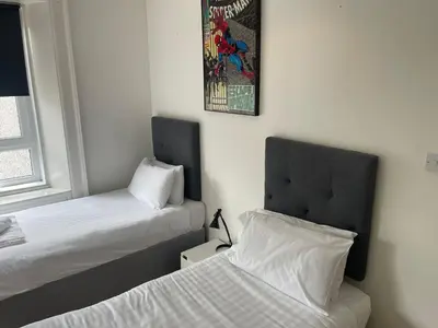 a bedroom with two beds and a picture on the wall at Elder Park Apartments in Glasgow