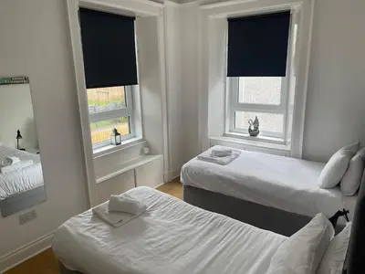 a bedroom with two beds and two windows at Elder Park Apartments in Glasgow