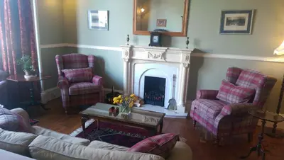 a living room with two chairs and a fireplace at Lochinver Guesthouse in Ayr