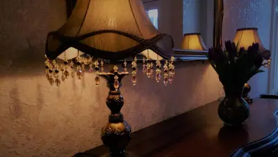 a lamp on a table next to a vase with flowers at Lochinver Guesthouse in Ayr
