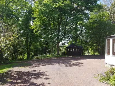 a small building in the middle of a road with trees at Bonkle House in Wishaw