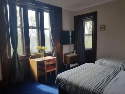 a bedroom with a bed and a desk with a vase of flowers at Bonkle House in Wishaw