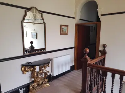 a hallway with a staircase with a mirror and a mirror at Bonkle House in Wishaw