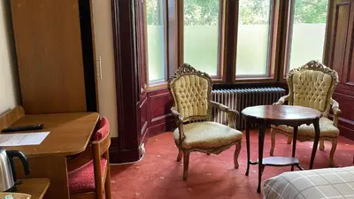 a room with two chairs and a table and window at Bonkle House in Wishaw