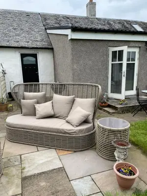 a large wicker couch sitting on a patio at Garden Cottage in Gartocharn