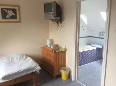 a bedroom with a bed and a tv and a tub at Riverside Cottage B&B in Cladich