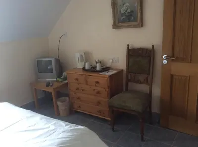 a bedroom with a bed and a chair and a tv at Riverside Cottage B&B in Cladich