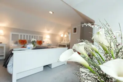 a white room with a bed and flowers in it at JustB Edinburgh in Edinburgh