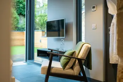 a living room with a chair and a tv at Garden Rooms Edinburgh in Edinburgh