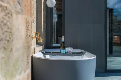 a bath tub with a bottle of wine and glasses at Garden Rooms Edinburgh in Edinburgh
