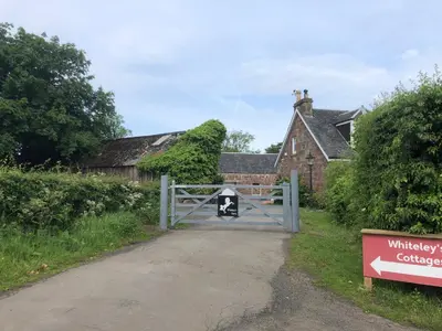 a gate to a house with a cow on it at Whiteley's Cottages in Dumbarton
