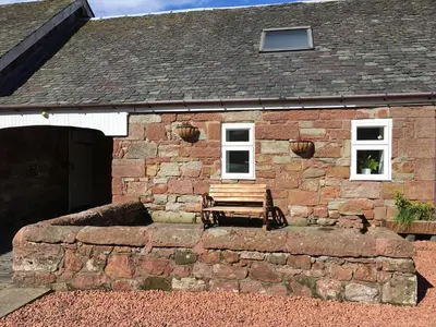 a brick building with a bench in front of it at Whiteley's Cottages in Dumbarton