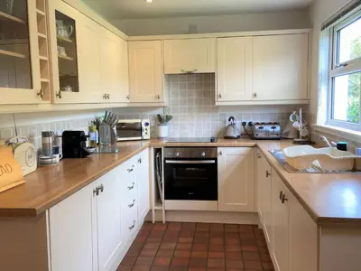 a kitchen with white cabinets and wooden counter tops at Tramway Cottages in Ellanbeich