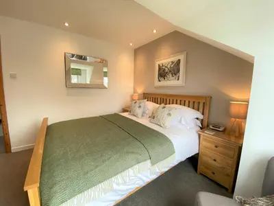 a bedroom with a large bed and a mirror at Tramway Cottages in Ellanbeich