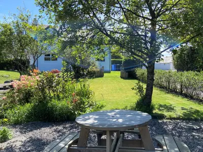 a wooden stool sitting in the middle of a garden at Tramway Cottages in Ellanbeich