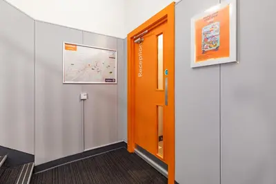 an office corridor with an orange door and a map at easyHotel Edinburgh in Edinburgh