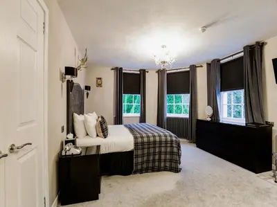 a bedroom with a bed and two windows at Barony Castle Hotel in Peebles
