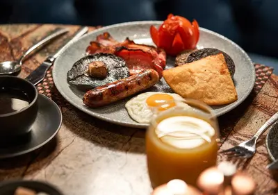 a plate of breakfast food with sausage and eggs on a table at Loch Fyne Hotel & Spa in Inveraray