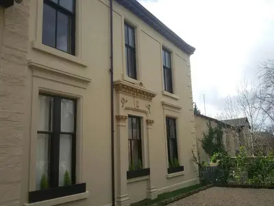 a white house with black windows and a fence at Crosshill House in Glasgow
