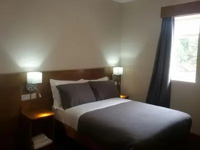 a bedroom with a bed with two lamps and a window at Crosshill House in Glasgow