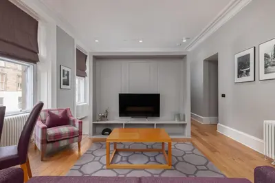 a living room with a tv and a table at Destiny Scotland - Distillers House in Edinburgh