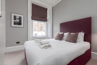 a white bedroom with a large bed with white sheets at Destiny Scotland - Distillers House in Edinburgh