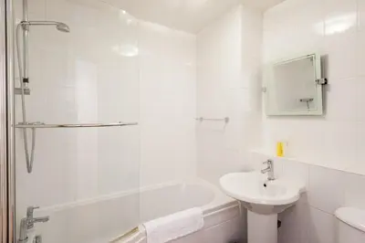 a white bathroom with a sink and a bath tub at Glasgow City Flats - Merchant City in Glasgow