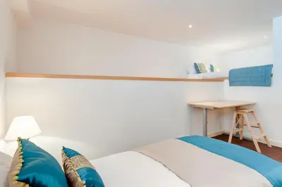 a bedroom with a bed with blue pillows and a desk at Glasgow City Flats - Merchant City in Glasgow