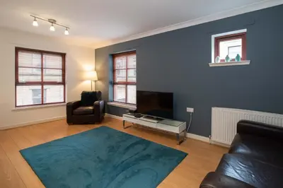 a living room with a couch and a television at Glasgow City Flats - Merchant City in Glasgow