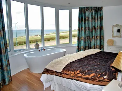 a bedroom with a bed and a bath tub and windows at Island View in Dunure
