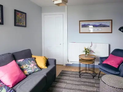 a living room with a couch and a table at Ivybank Cottage in Lamlash