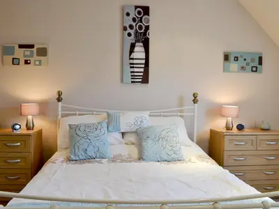 a bedroom with a white bed with blue pillows at Lia Fail in Ballachulish
