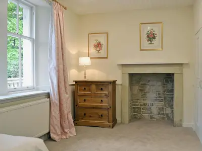 a bedroom with a fireplace and a dresser and a window at Fernwoodlea in Blairhall