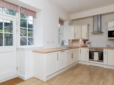 a kitchen with white cabinets and a large window at One The Stables in Dalrymple