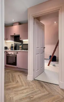 an open door to a kitchen with pink cabinets at Munro Guest House in Stirling
